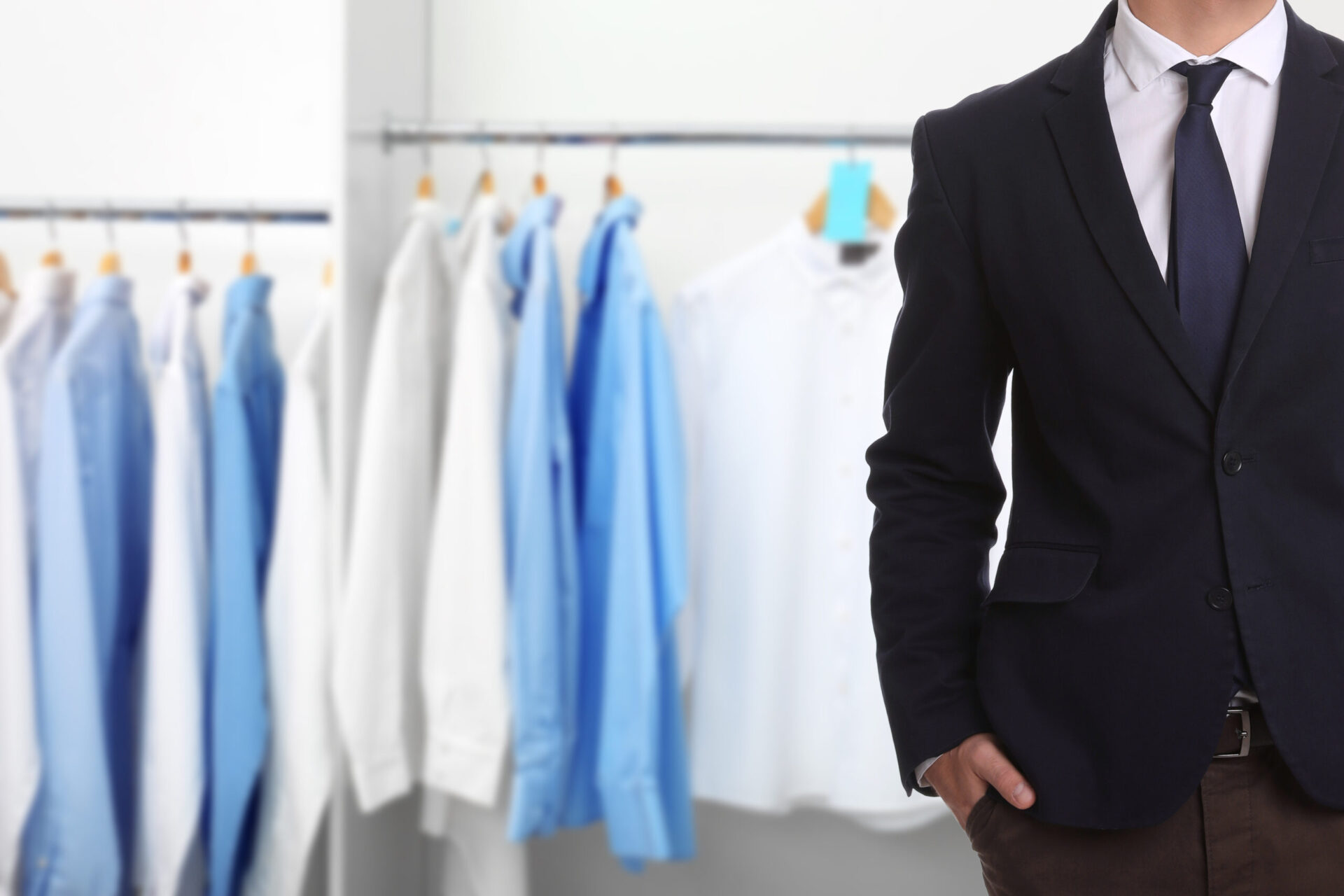 Businessman and rack with clean clothes at dry-cleaner's, closeup.